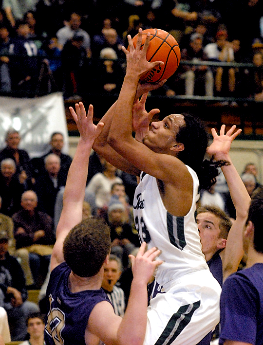 Port Angels' Lambros Rogers aims for the hoop while being surrounded by Sequim's Jack Shea