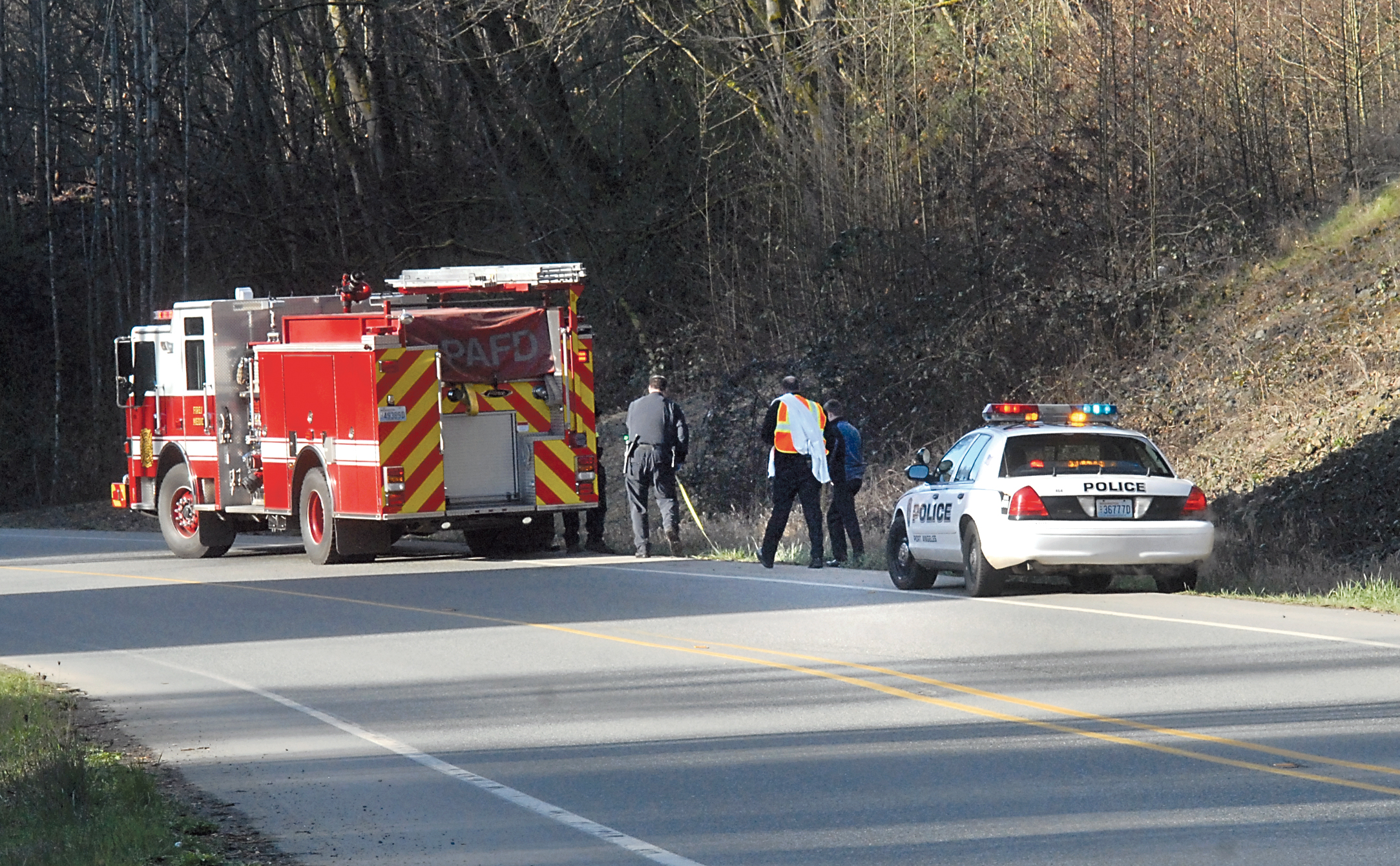 Investigators examine the scene where a body was found along the Tumwater Truck Route beneath the western Eighth Street bridge in Port Angeles on Tuesday. (Keith Thorpe/Peninsula Daily News)