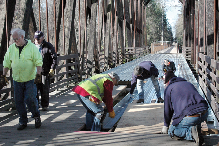 Volunteers with the Peninsula Trails Coalition prepare the wooden ramp and 155-foot historical bridge at Railroad Bridge Park near Sequim to be resurfaced with concrete. (Alana Linderoth/Olympic Peninsula News Group)