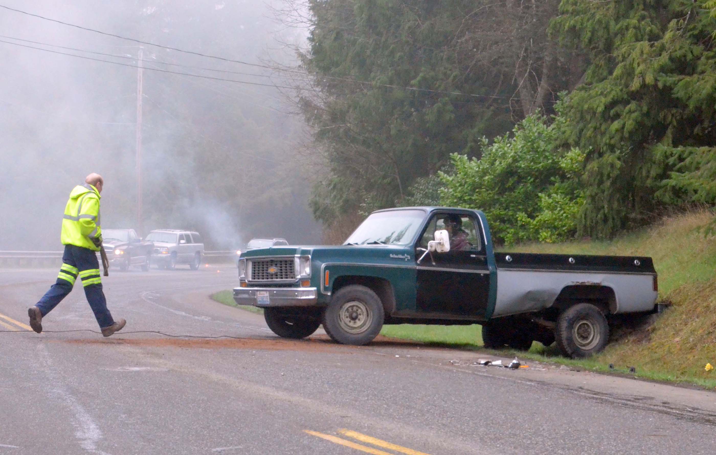 All City Towing employee Nathan Reed walks across Irondale Road on Monday morning to hook up the truck of Graham Logg of Port Townsend.  — Photo by Charlie Bermant/Peninsula Daily News ()