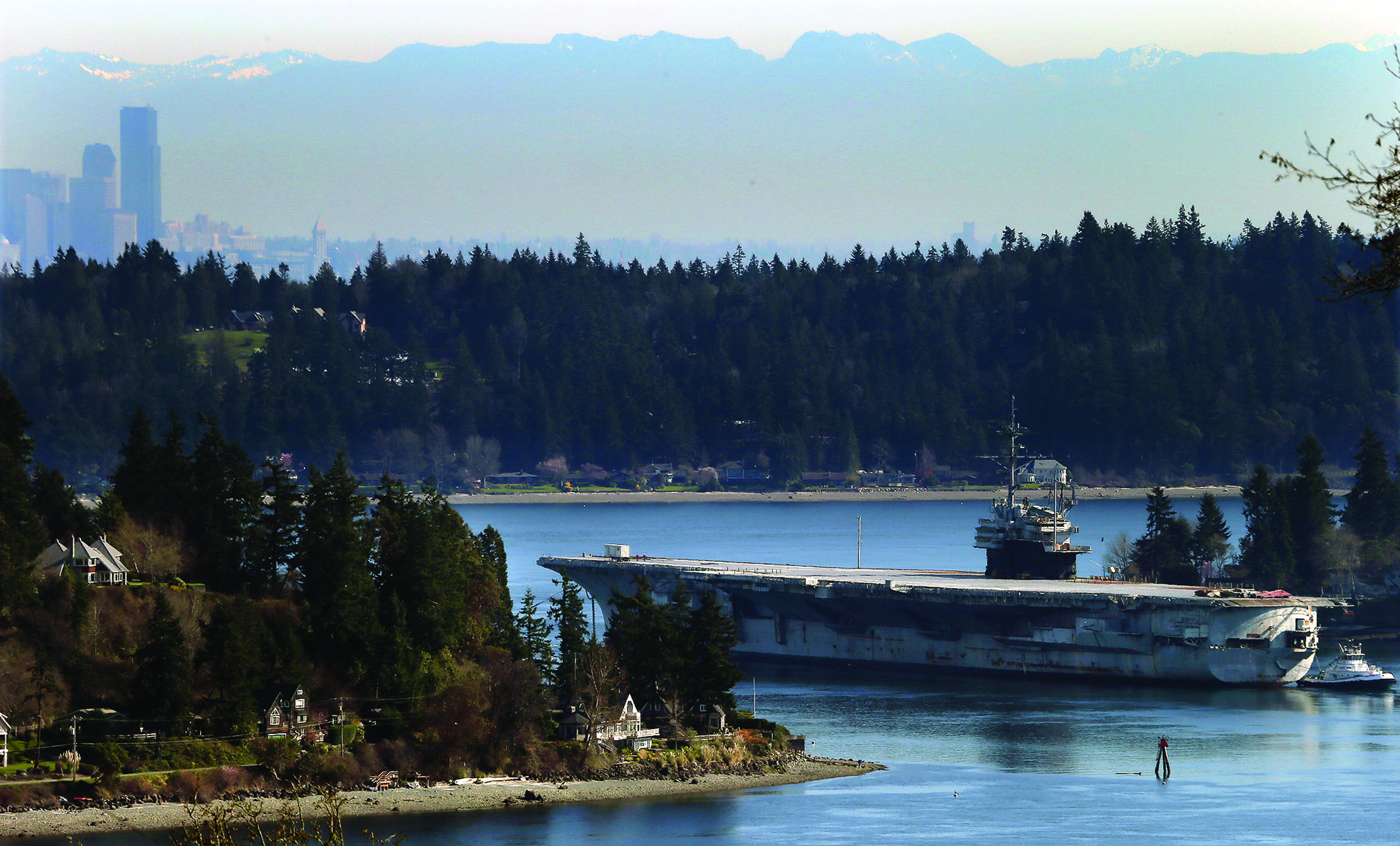 The USS Ranger is towed through Rich Passage for the last time Thursday in Bremerton as the historic aircraft carrier heads to Texas to be dismantled. (The Associated Press)