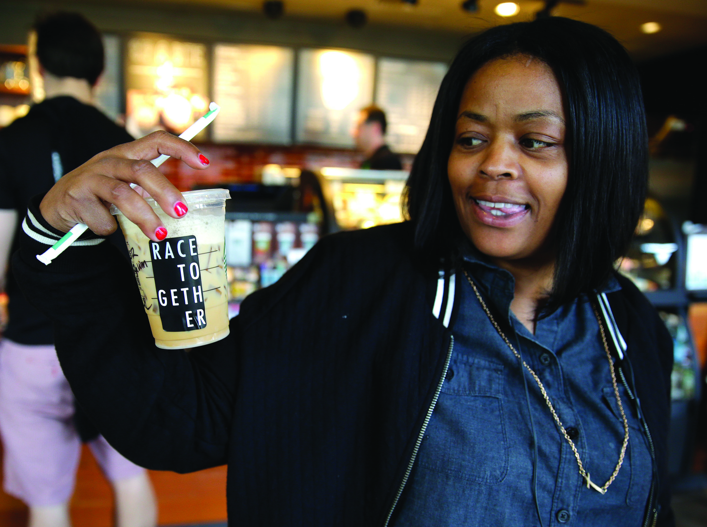 Larenda Myres holds an iced coffee drink with a “Race Together” sticker on it at a Starbucks in Seattle on Wednesday. — The Associated Press ()