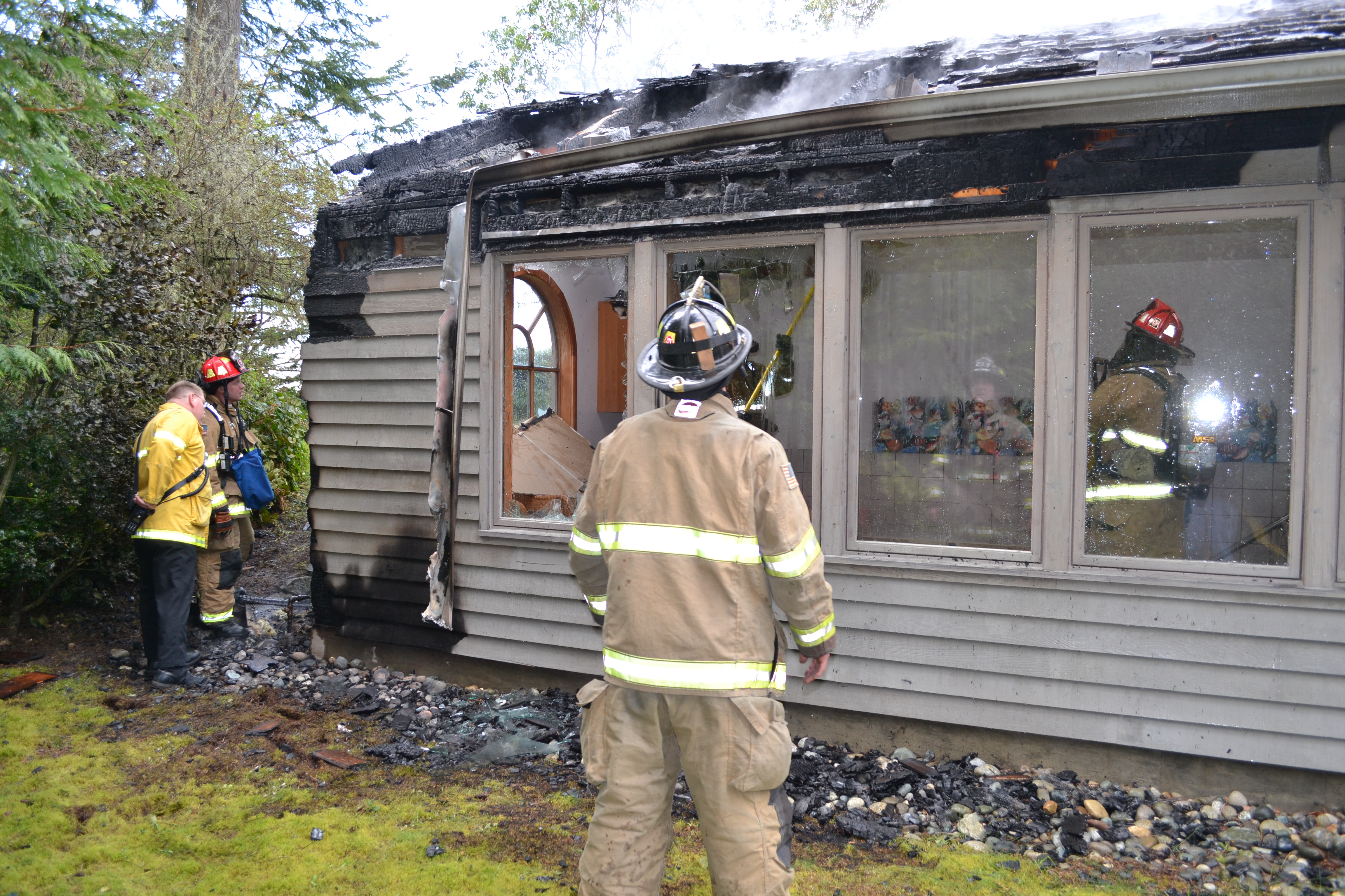 Firefighters with East Jefferson Fire-Rescue examine an outbuilding housing a small pool at a home west of Port Townsend that was damaged by fire Monday afternoon. (Bill Beezley/East Jefferson Fire-Rescue)