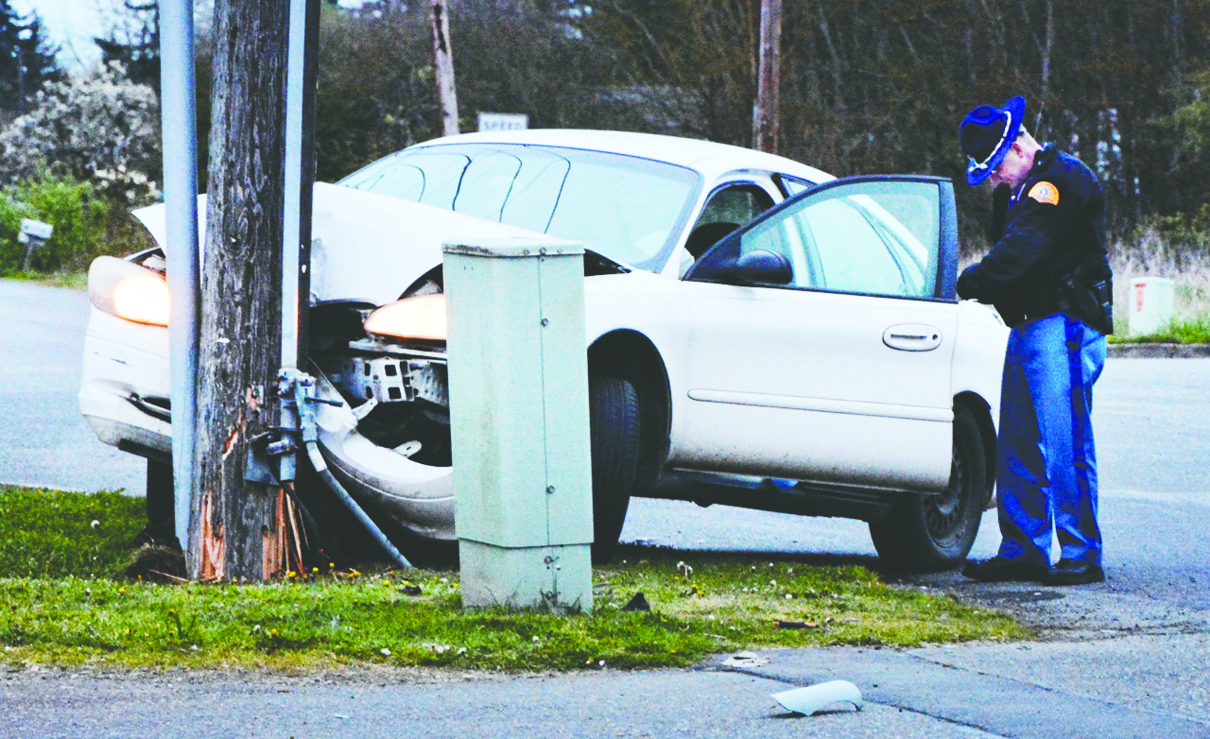 A State Trooper fills out paperwork as he examines a 2001 Ford Taurus that struck a power pole near the intersection of Mount Pleasant Road and U.S. Highway 101 on Sunday at about 7:38 p.m. The wreck cut off power to residents in the Deer Park area until noon Monday. — Jay Cline/Clallam County Fire District No. 2 ()