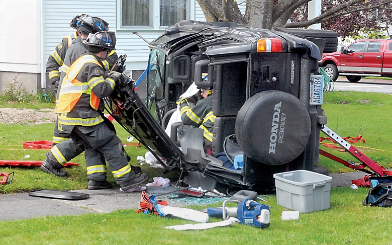 Port Angeles firefighters pull the roof from a sport utility vehicle to remove the driver and a firefighter inside rendering aid after the SUV ended up on its side after being involved in a two-car collision Wednesday at Fifth and Peabody streets in Port Angeles. (Keith Thorpe/Peninsula Daily News)