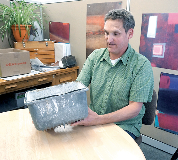 Jefferson County Parks and Recreation Director Matt Tyler inspects the 10-pound cowling that fell from a 100-foot-tall lightpost at Memorial Field. (Charlie Bermant/Peninsula Daily News)