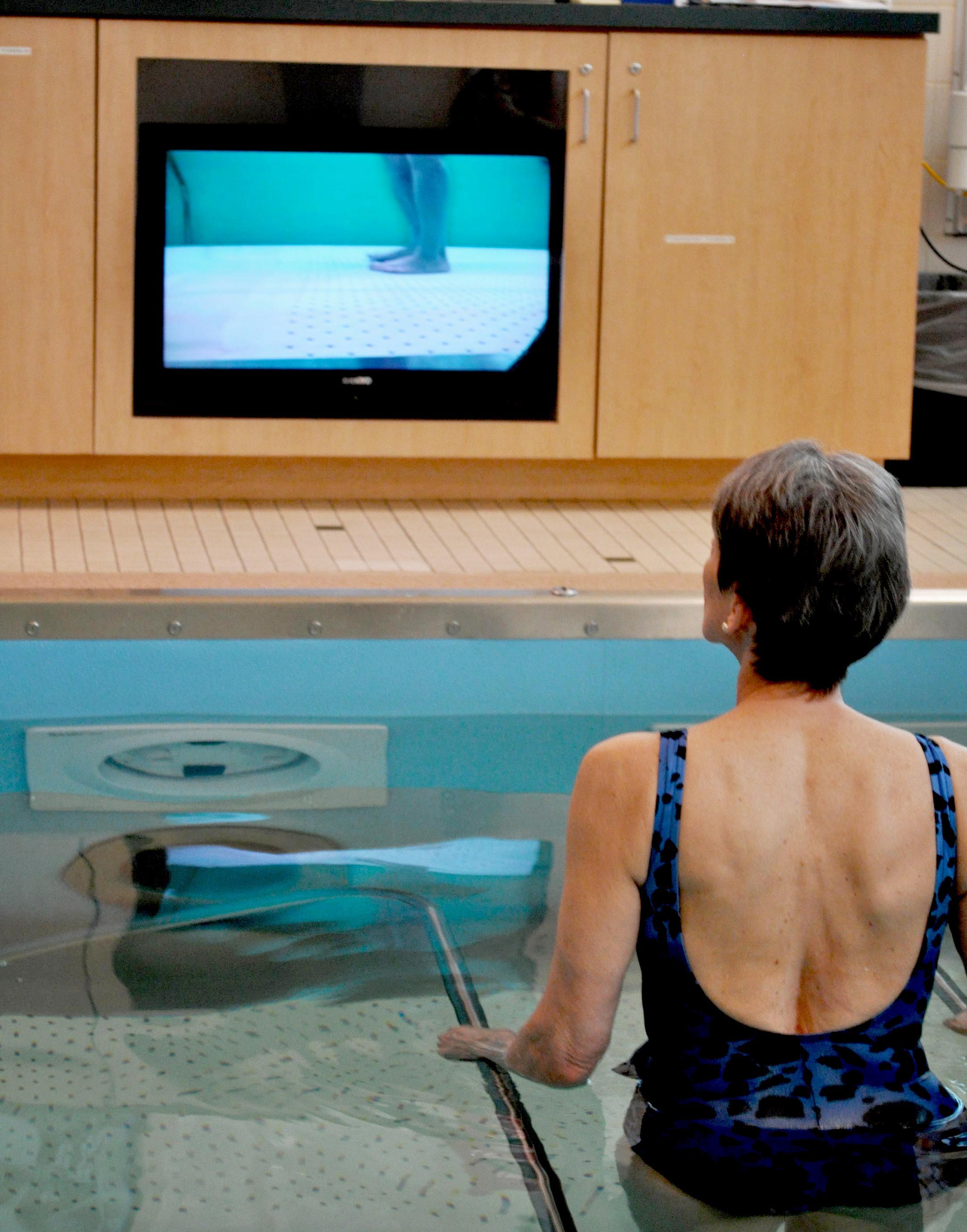 Sandy Smith of the Olympic Medical Center staff demonstrates one of the therapy pool's features: monitoring her underwater movements on a video monitor. (James Casey/Peninsula Daily News)