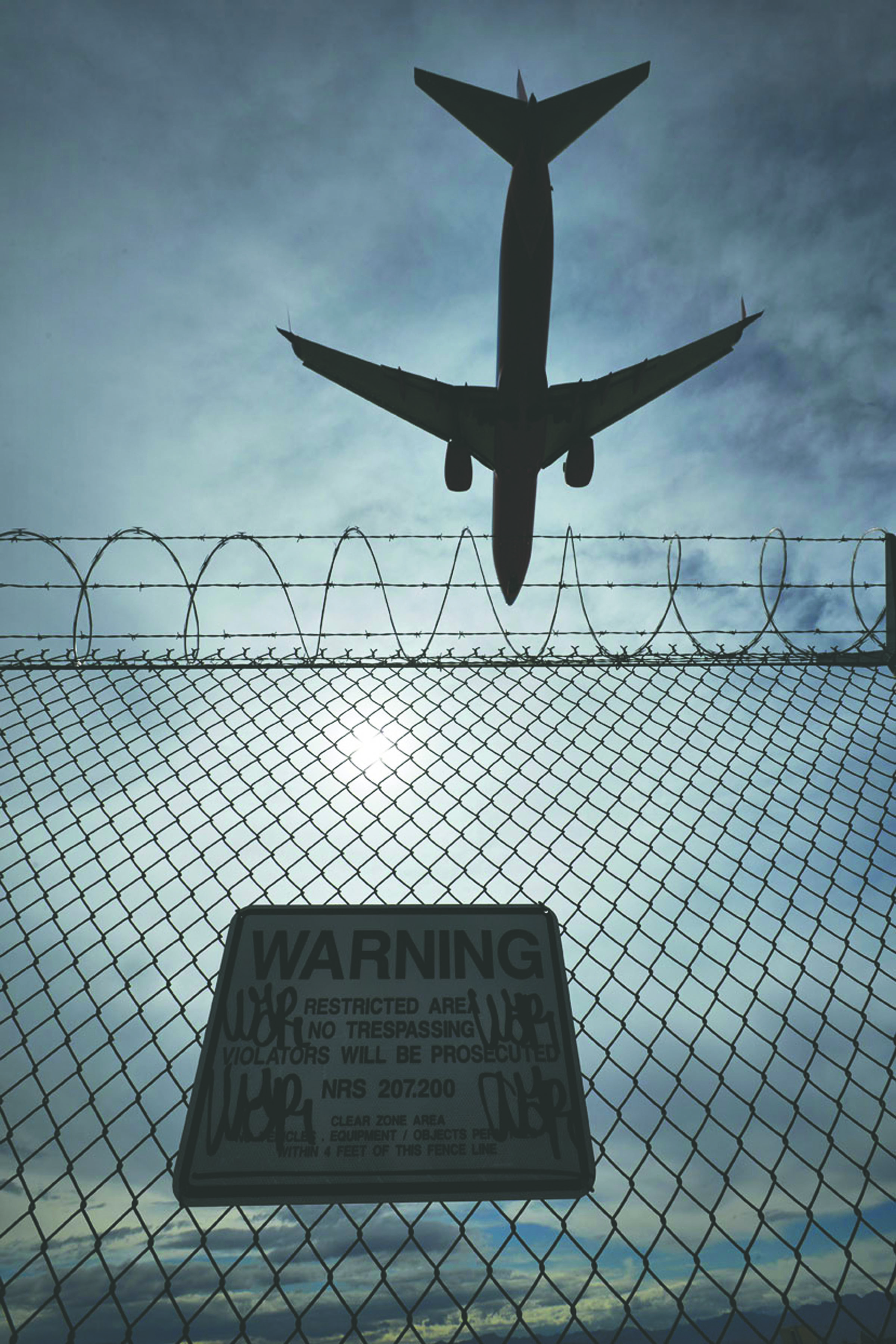 A sign warns against trespassing as a plane lands at McCarran International Airport in Las Vegas. — The Associated Press ()