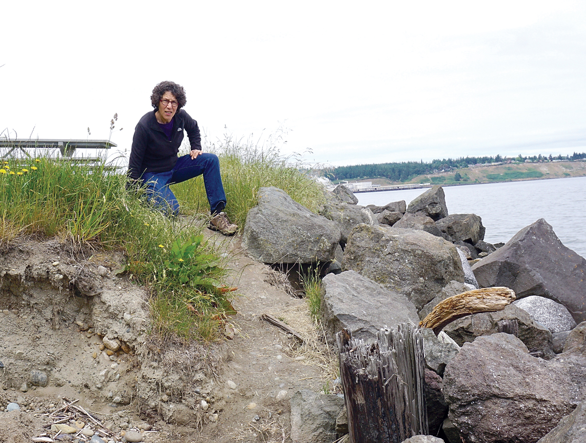 Jefferson County Marine Resources Committee Water Programs Coordinator Cheryl Lowe sits atop a bluff at Fort Towsend scheduled for removal this summer. — Charlie Bermant/Peninsula Daily News ()