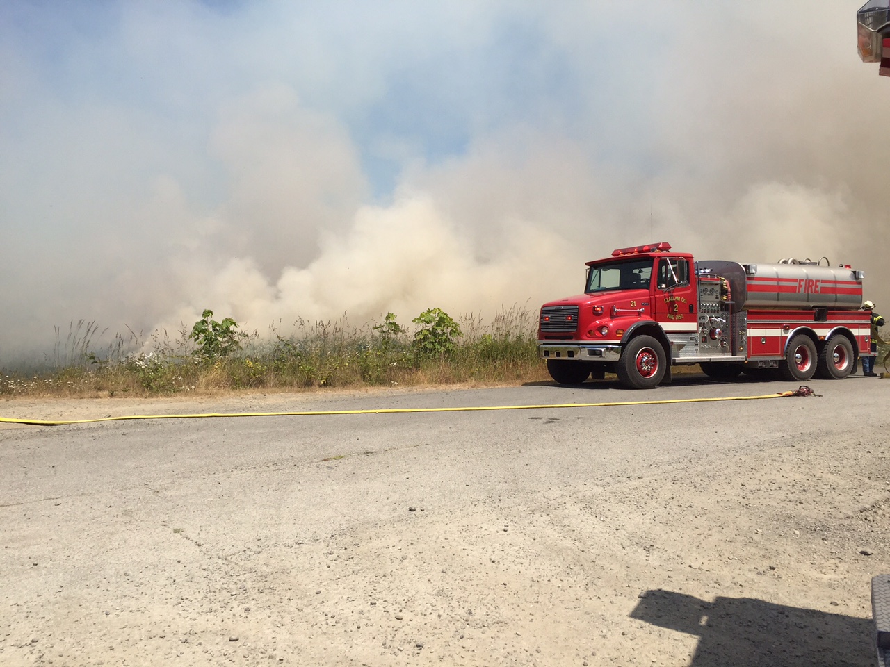 A Clallam County Fire District No. 2 truck sits beside the smoky fire that burned near the Elwha River this afternoon.  —Photo by Jay Cline ()