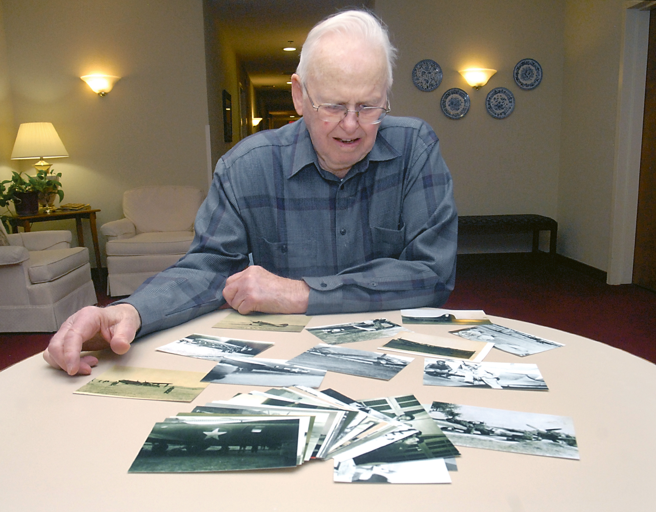 Miram Ritchie of Sequim looks over a table of war photographs. (Keith Thorpe/Peninsula Daily News)