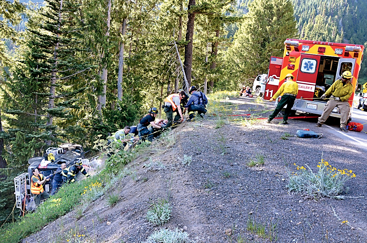 Rescuers from Clallam County Fire District No. 2 use rope lines to bring two Olympic National Park visitors from Ohio 25 feet up an embankment on Hurricane Ridge Road. —Photo by Jay Cline/for Peninsula Daily News ()