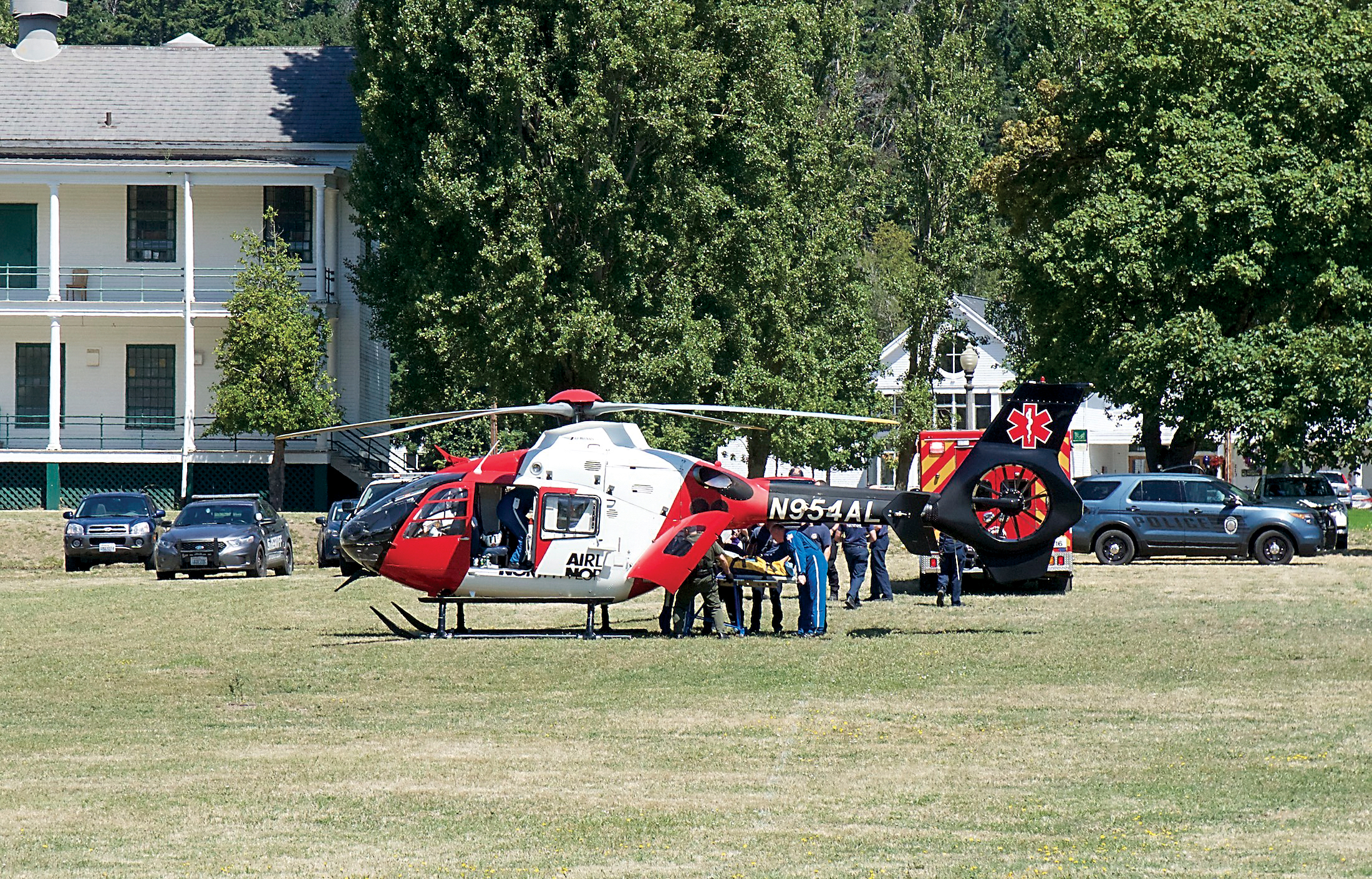 Port Townsend police and East Jefferson Fire-Rescue personnel load a man into a helicopter on the parade ground of Fort Worden State Park on Friday for transportation to a Seattle hospital. — Steve Mullensky/for Peninsula Daily News ()