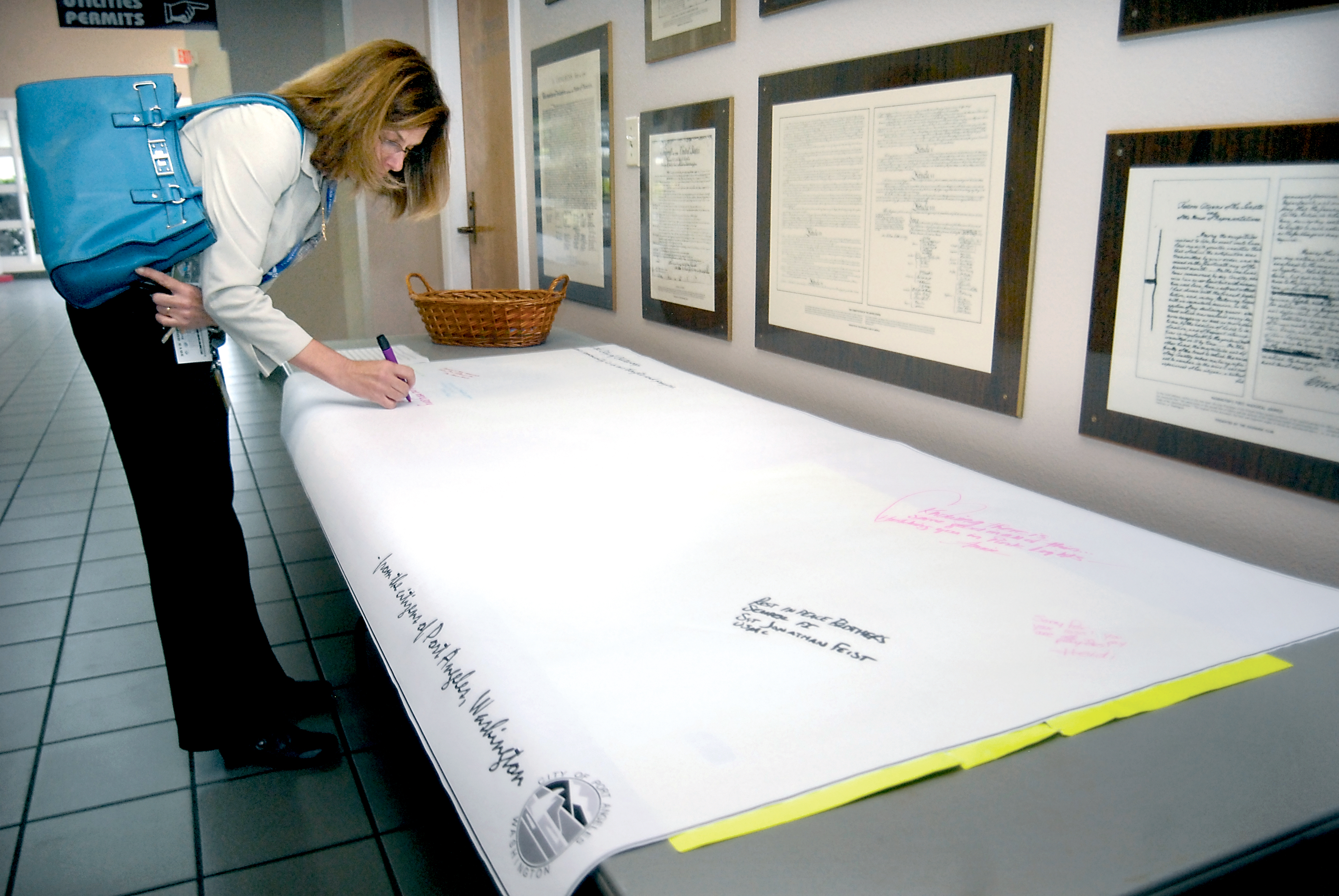 Debbie Hunt of Port Angeles writes a message of condolence Tuesday on a banner that will be sent to the city of Chattanooga