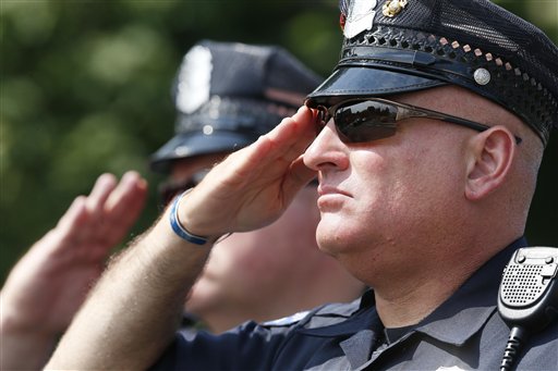 Police officers salute as the casket with the remains of one of five service members shot to death in the July 16 attack in Chattanooga