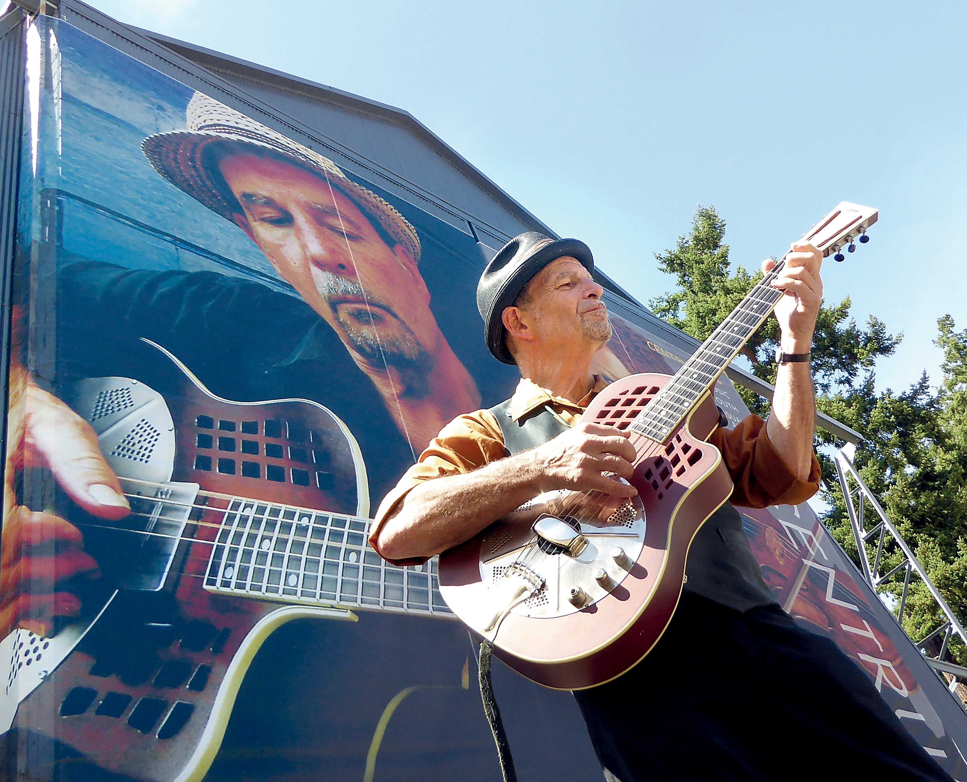 Guitarist Steve James picks out a tune while standing in front of a 47-foot-high mural created from his image that is attached to the side of McCurdy Pavilion at Fort Worden State Park. James is an instructor and performer at the Port Townsend Acoustic Blues Festival