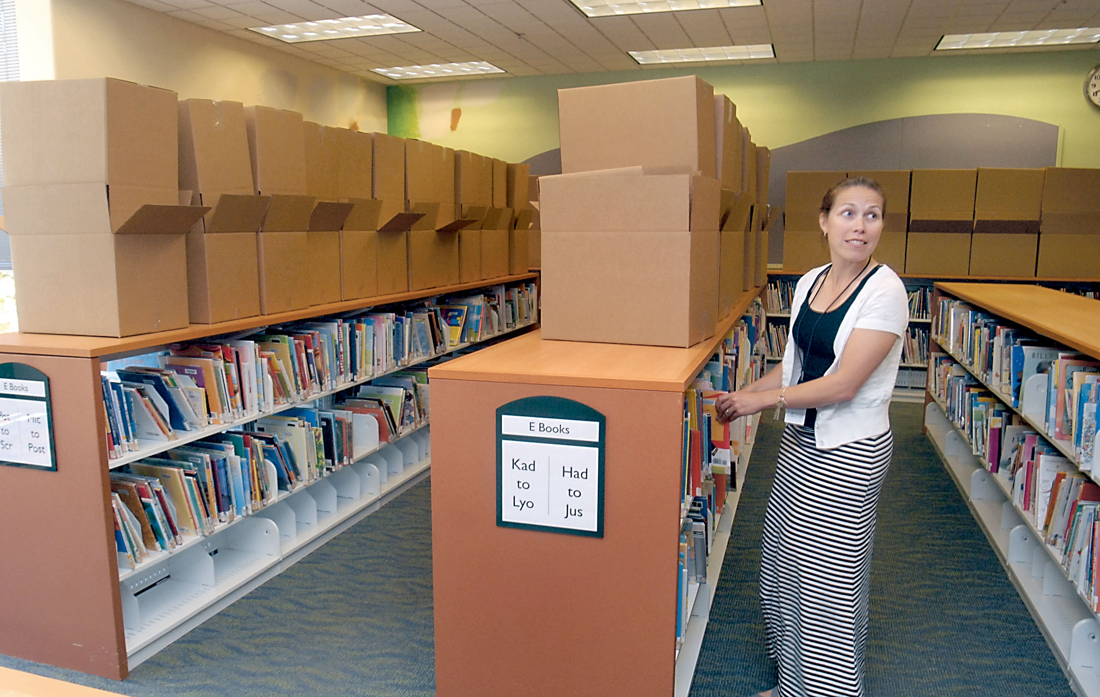 Childrens librarian Jennifer Lu'Becke straightens a shelf while boxes wait to be filled with books at the Port Angeles Public Library on Friday. Keith Thorpe/Peninsula Daily News