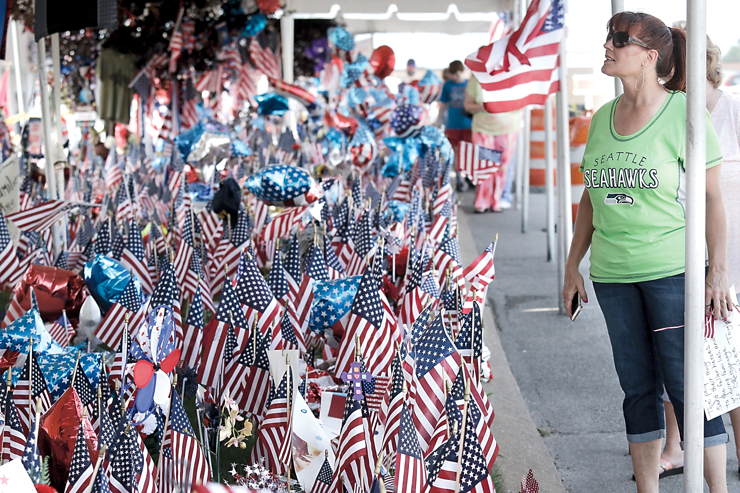 Revitalize Port Angeles founder Leslie Robertson on Wednesday carried a sign from Port Angeles to the Lee Highway memorial for victims of the July 16 shootings at the adjacent Armed Forces Career Center in Chattanooga