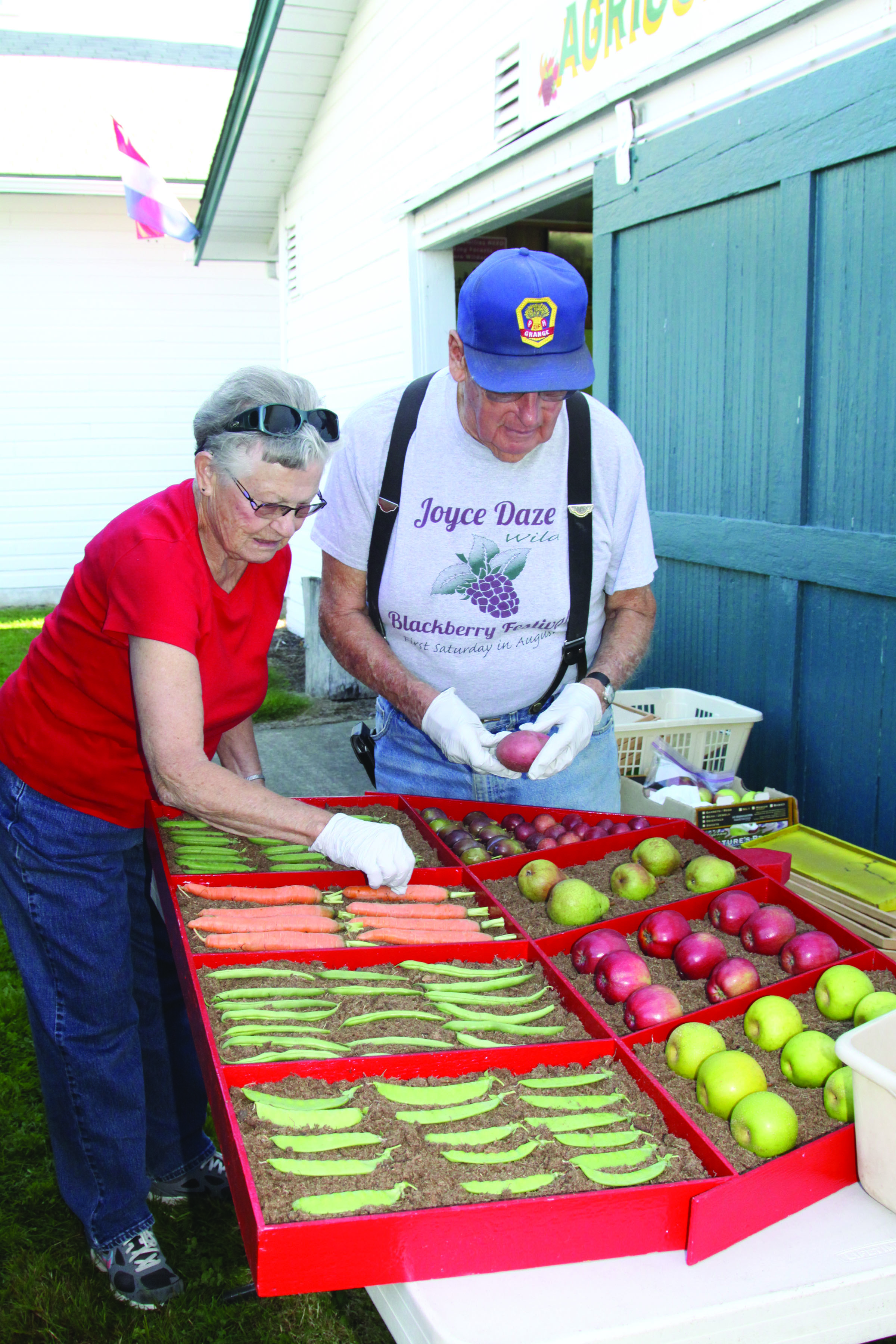 Lalah and John Singhose of the Crescent Grange arrange a display for their booth at the Clallam County Fairgrounds on Tuesday. Dave Logan/for Peninsula Daily News