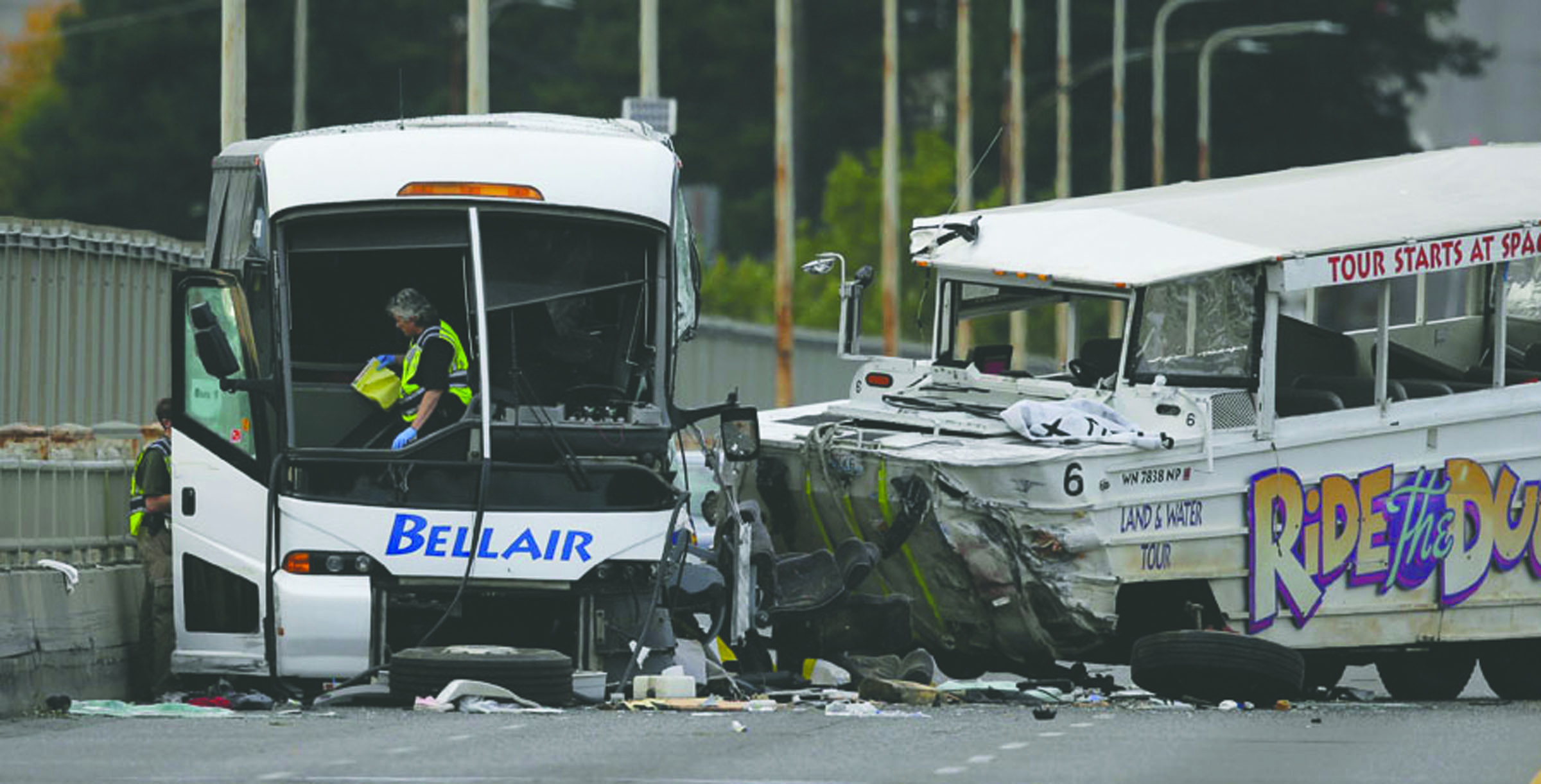 A Seattle Police investigator walks off of a charter passenger bus at left that was involved in a fatal crash with the Ride the Ducks tourist vehicle at right