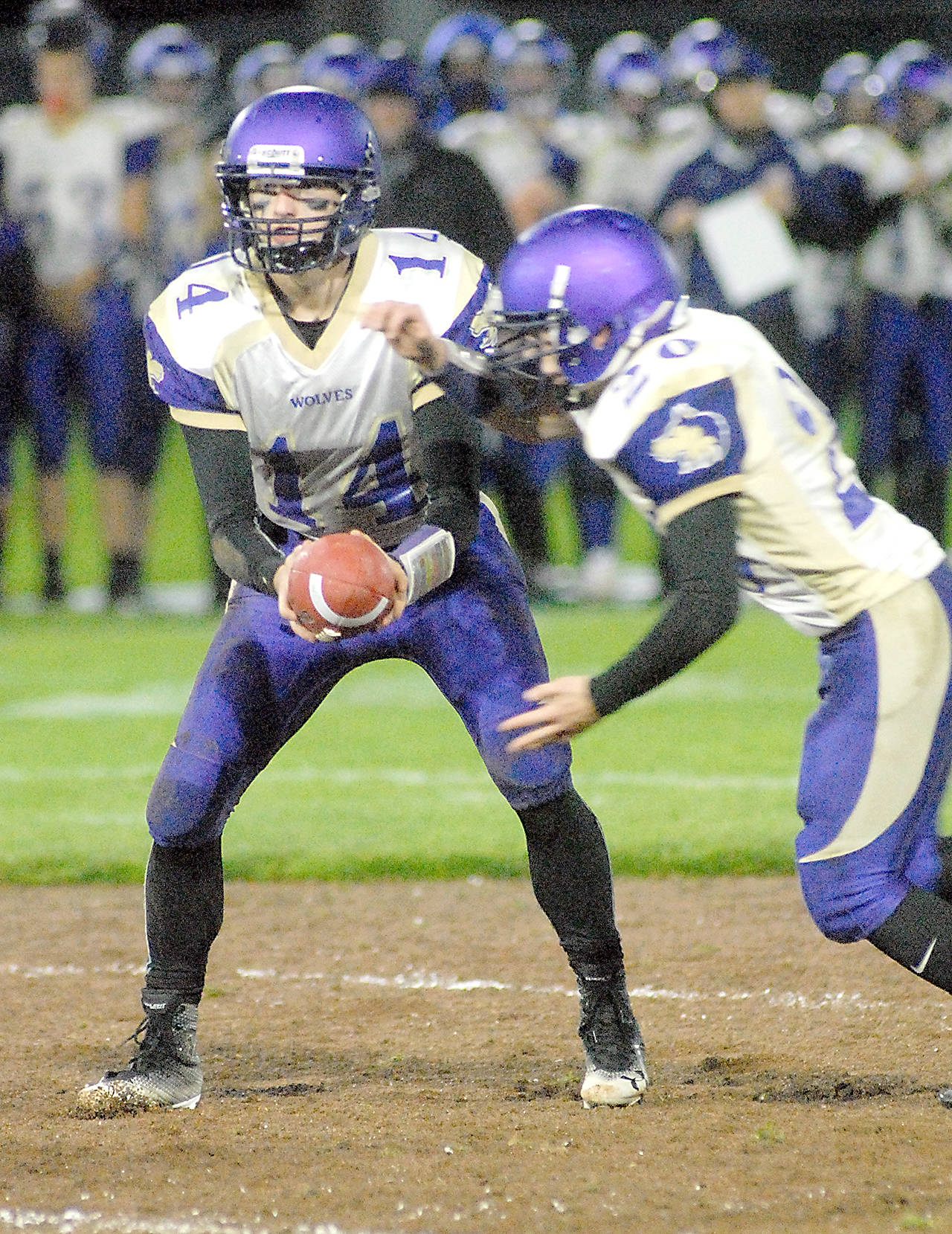 Keith Thorpe/Peninsula Daily News Sequim quarterback Riley Cowan, left, hands off to teammate Hayden Gresli during last week’s game against Port Angeles.