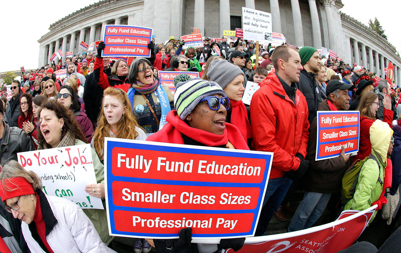 Oveta Hunter, center, an elementary school teacher from Seattle, cheers and holds a sign during a rally in support of education funding at the Capitol in Olympia in January. (Ted S. Warren/The Associated Press)