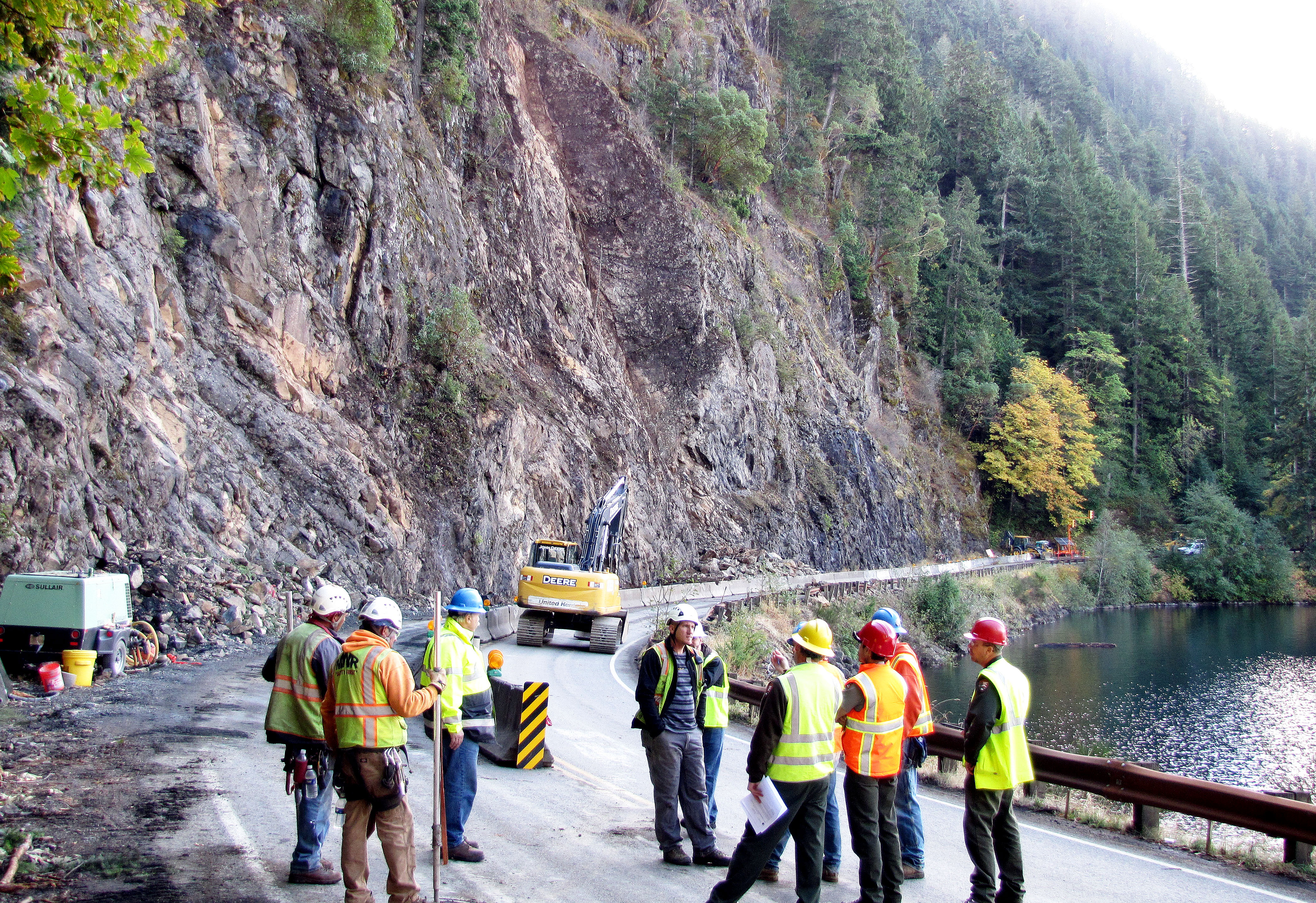 State and Olympic National Park road workers stand on U.S. 101 on the edge of Lake Crescent on Wednesday