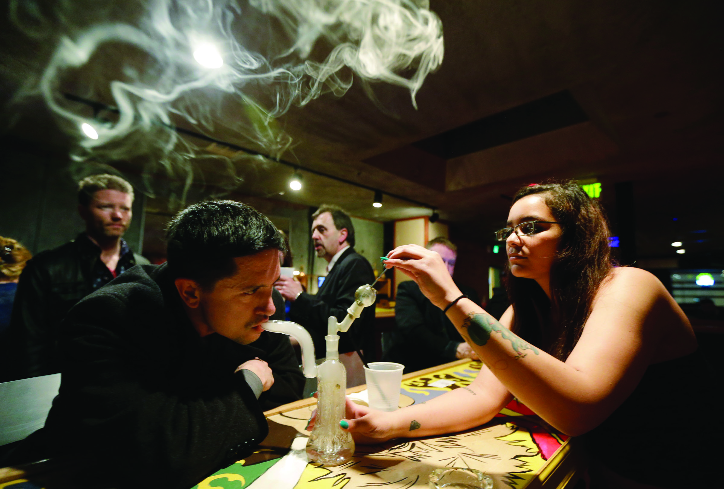 John Connelly inhales marijuana vapor just after midnight with the help of bar worker Jenae DeCampo in the upstairs lounge area of Stonegate