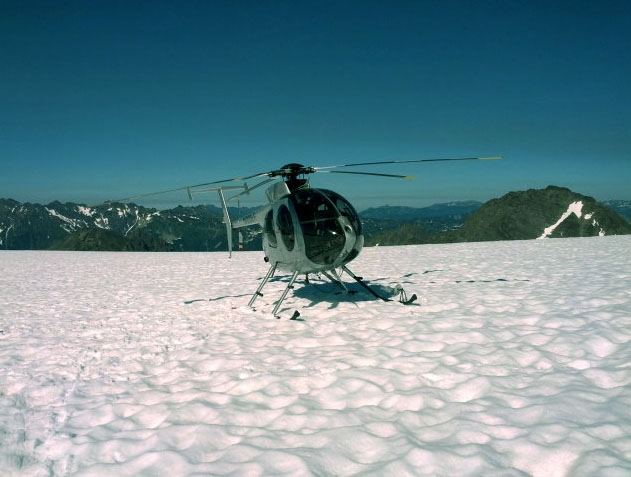 A helicopter waits on a glacier at Mount Olympus to retrieve the body of Portland