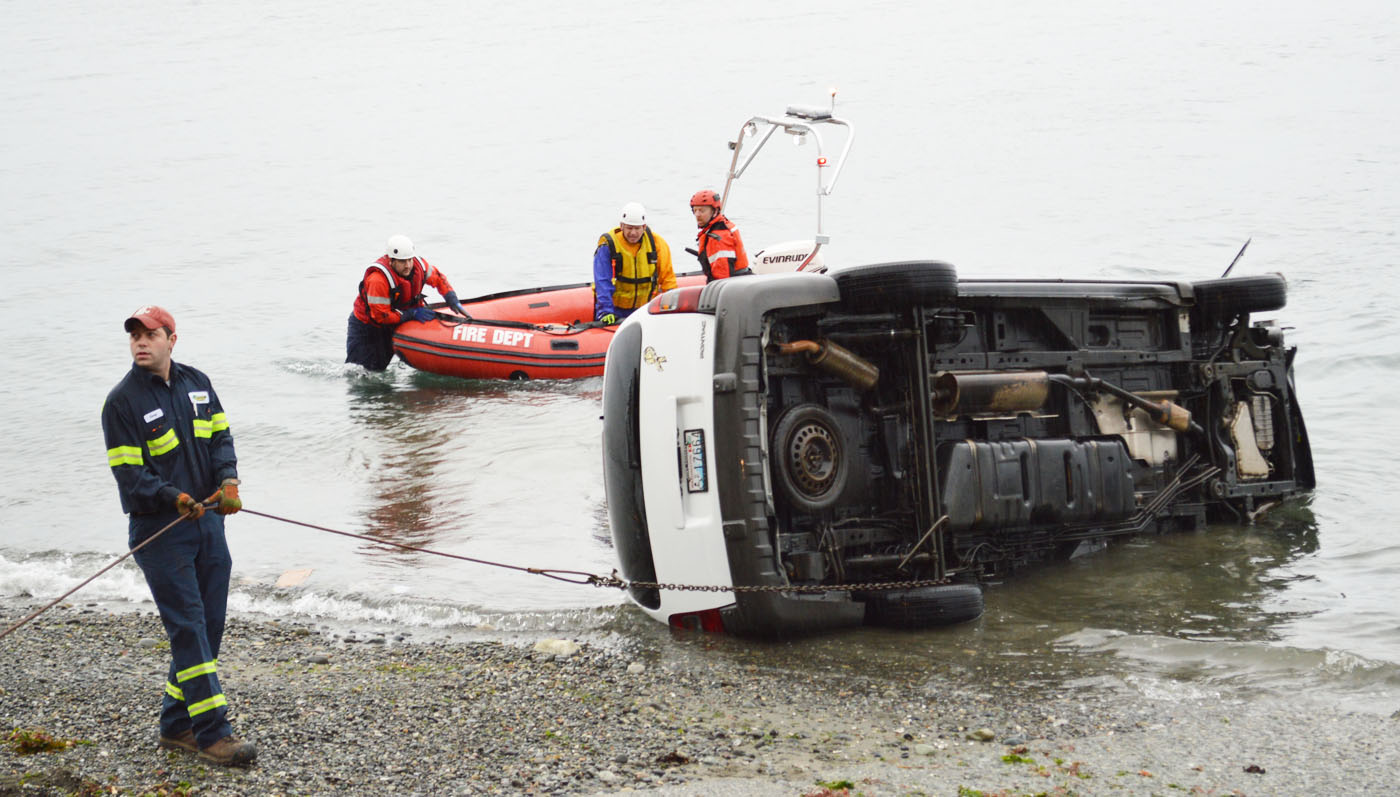 Evergreen Collision workers and crews from Clallam County Fire District No. 3 pull a minivan out of the Strait of Juan de Fuca at the Port Williams boat launch this morning. Joe Smillie/Peninsula Daily News