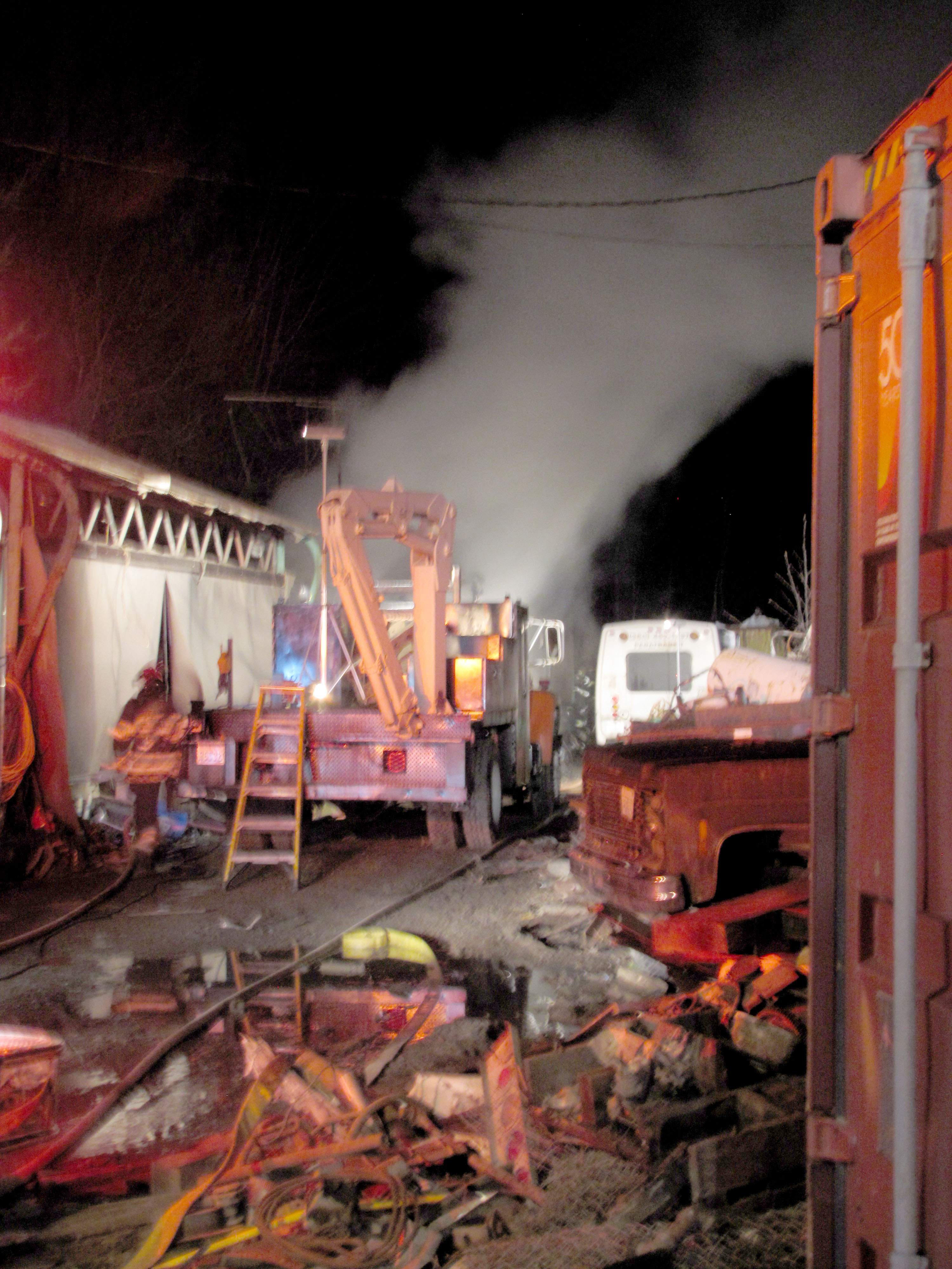 Clallam County Fire District No. 2 firefighters pick through a narrow passage in a west Port Angeles junkyard to get access to a trailer house fire Tuesday night. Arwyn Rice/Peninsula Daily News