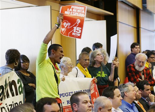 Carlos Hernandez-Sosa holds a sign in support of the $15 minimum wage measure at Monday's Seattle City Council meeting. The Associated Press