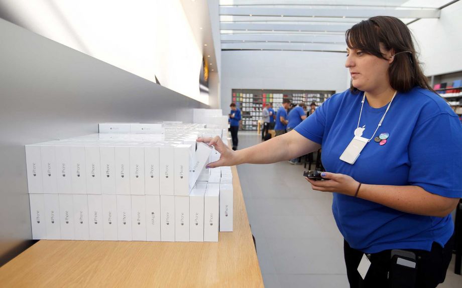 An Apple employee grabs an iPhone 6 for a customer at the Apple Store in Palo Alto