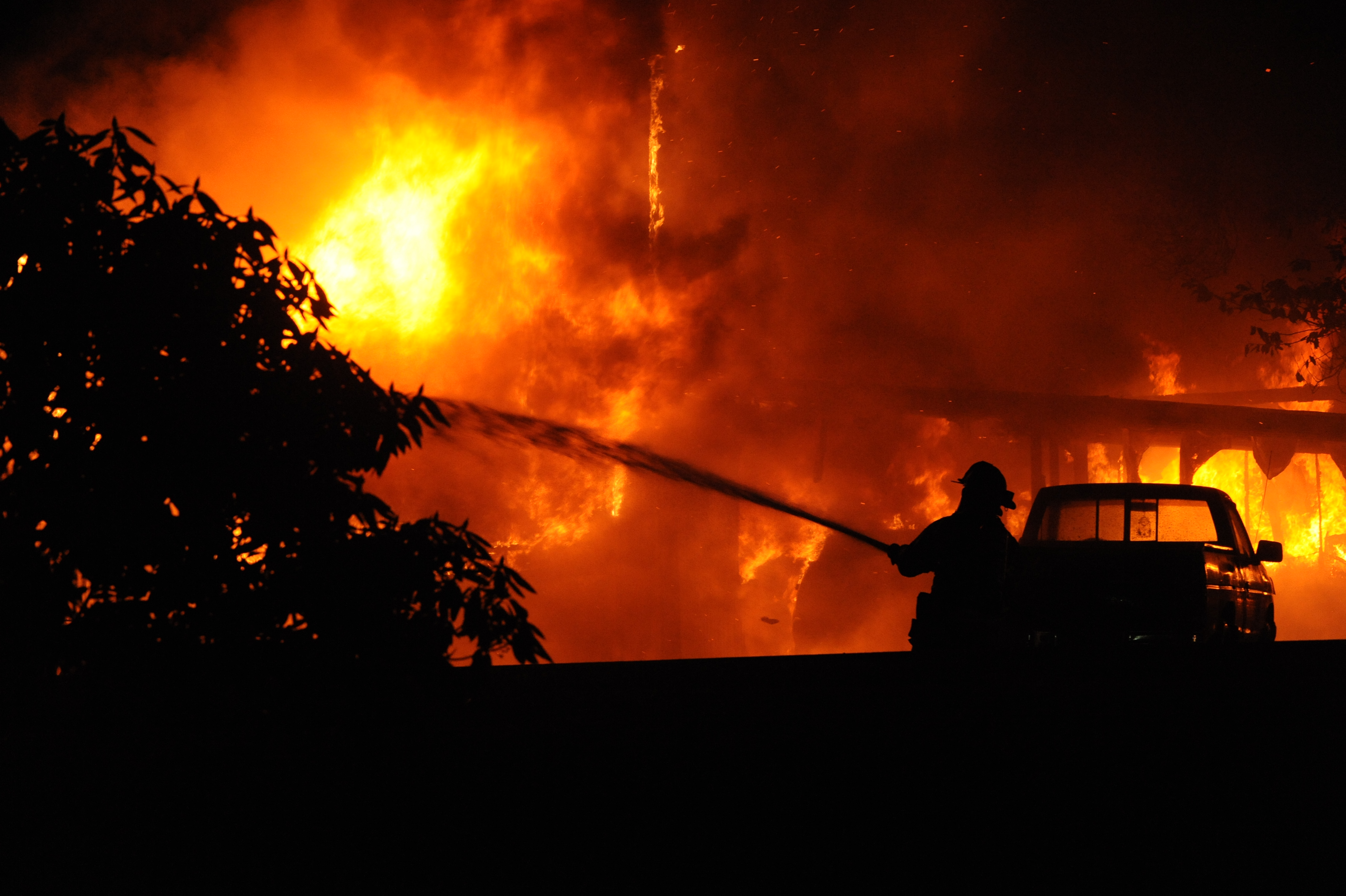 A Clallam County Fire District No. 1 firefighter trains a hose on a fire in Beaver