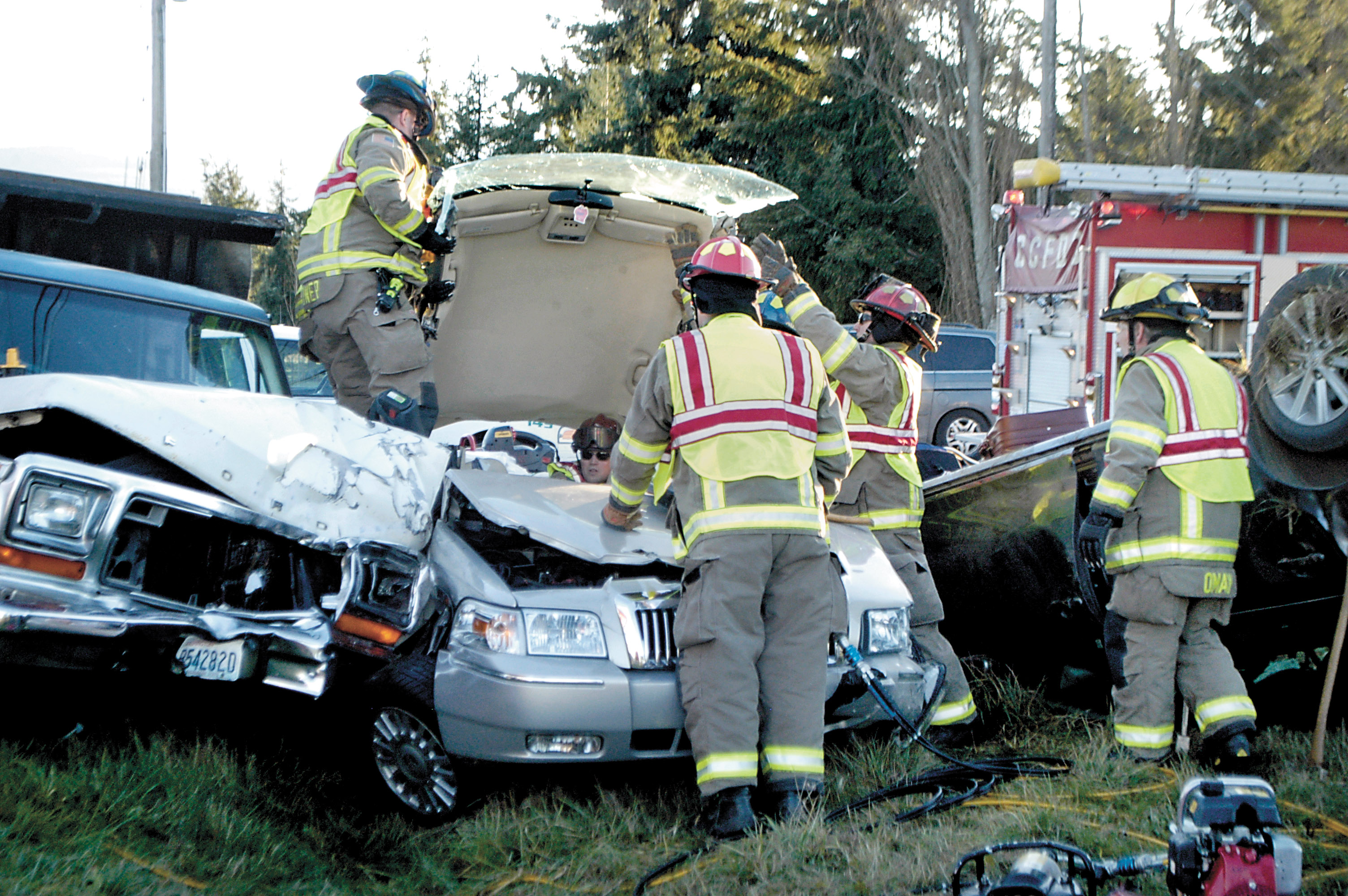 Firefighters with Clallam County Fire District 3 remove the roof of a Mercury sedan to extricate the trapped driver after a three-vehicle collision at the intersection of Kitchen-Dick Road and Old Olympic Highway this afternoon. After extrication