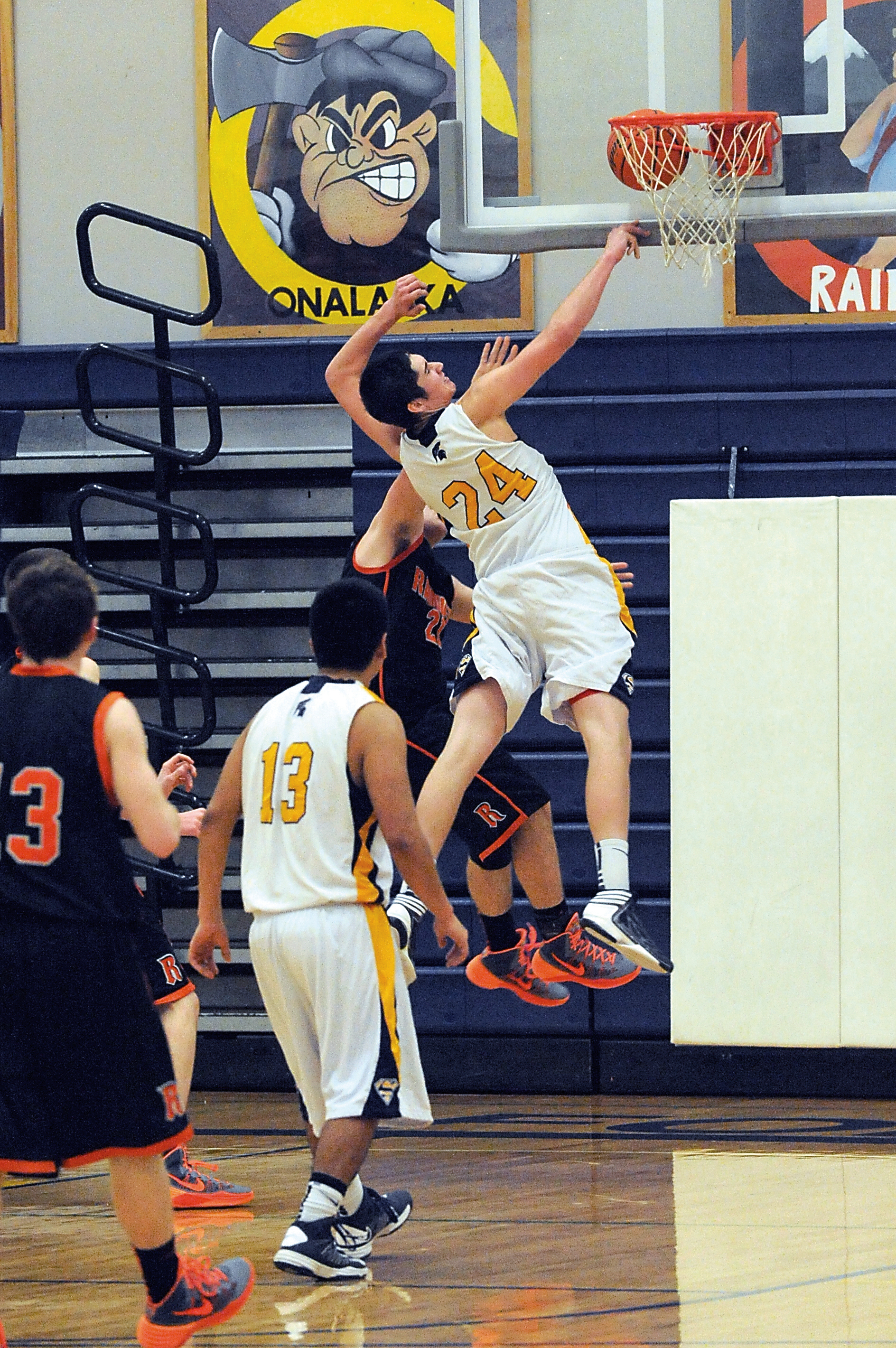 Forks' Leo Gonzales (24) stuffs a shot by Rainier's Bailey Miller. The ball became wedged in between the rim and the backboard