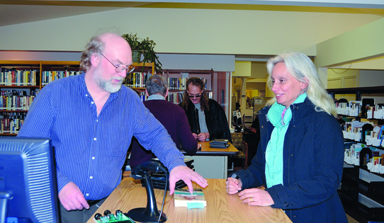 Jim Nyby checks out books for patron Jeanette Mifsud of Quilcene at the temporary quarters of the Jefferson County Library in Port Hadlock. It was once a yarn shop. Charlie Bermant/Peninsula Daily News