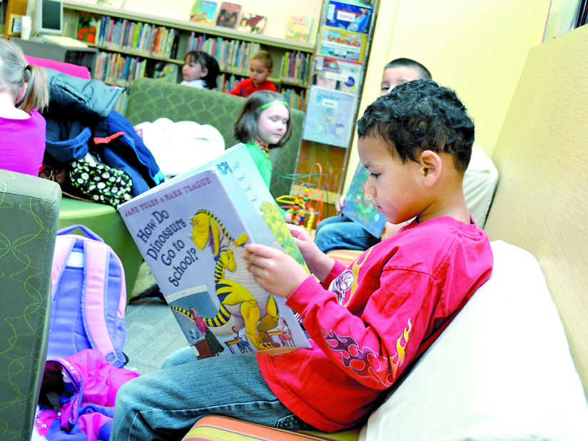 Legend Liggons reads a book in the Sequim Library with classmates on a field trip from Bibity Bobity Day Care. With usage at the Sequim branch escalating