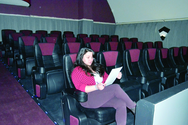 Uptown Theatre manager Carli Rose sits in the newly installed VIP section while inspecting the menu that will be served to patrons in that section. The renovated theater opened in January. Charlie Bermant/Peninsula Daily News