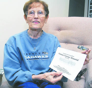 Linda Benson of Sequim holds a Vietnam War-era POW bracelet bearing the name of Navy Cmdr. Vincent Monroe and a pencil rubbing made from the Vietnam War Memorial in Burlington. Keith Thorpe/Peninsula Daily News