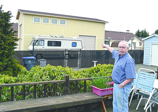 Donald Wright of Sequim points to agarage recently built by his neighbor which now obscures Wright's backyard view of the Olympic Mountains. Joe Smillie/Peninsula Daily News