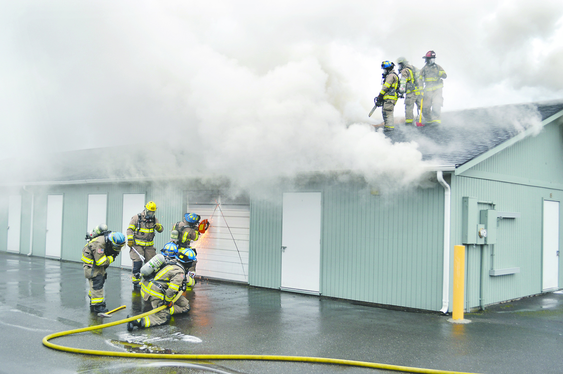 Clallam County Fire District No. 3 Firefighter Troy Tennesson cuts open a door to a burning unit at Sequim Stow Places on Wednesday. Joe Smillie/Peninsula Daily News