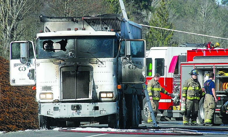 Clallam County Fire District No. 3 firefighters mop up the scene after a sawdust truck belonging to Hermann Bros. experienced an engine compartment fire Tuesday on U.S. Highway 101 east of Sherburne Road between Port Angeles and Sequim. Keith Thorpe/Peninsula Daily News