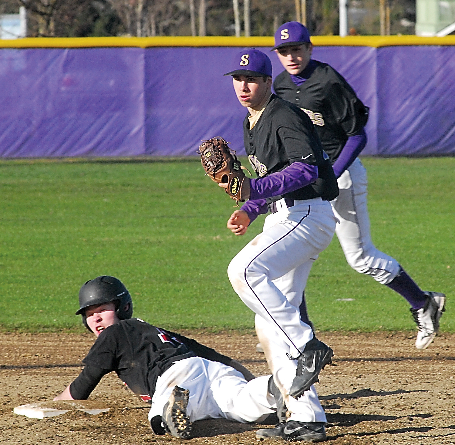 Port Townsend's Sean Dwyer looks back at the umpire after being tagged out on a steal attempt by Sequim's Dylan Lott