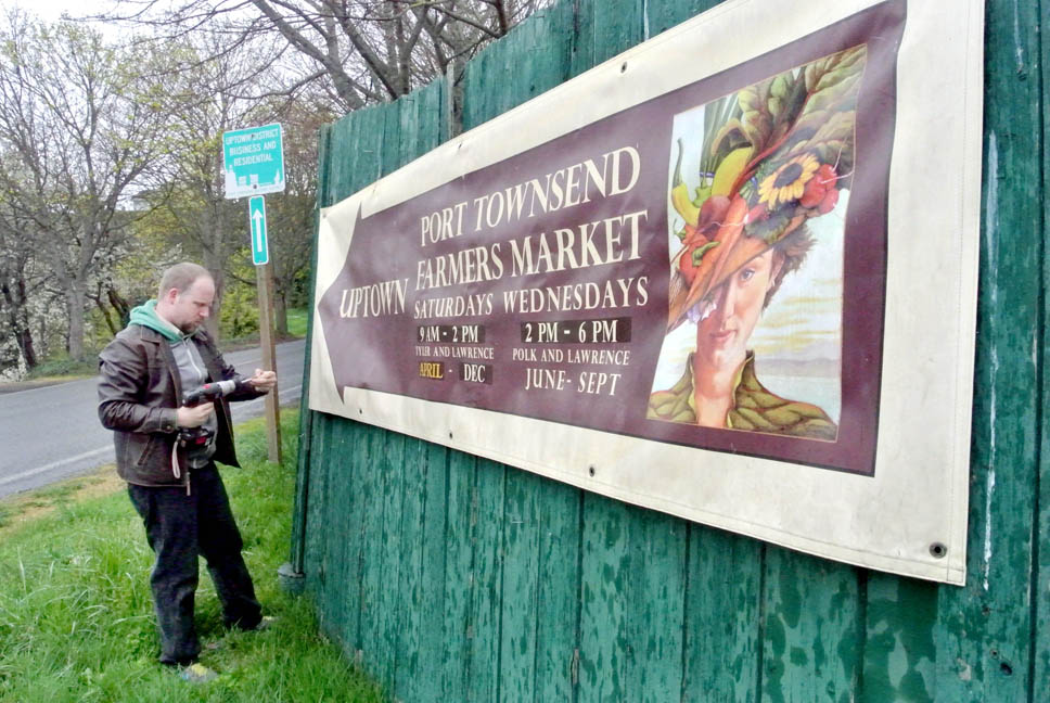 Port Townsend Farmers Market Manager Will O'Donnell puts up a sign on Quincy Street announcing the seasonal market's return. Charlie Bermant/Peninsula Daily News