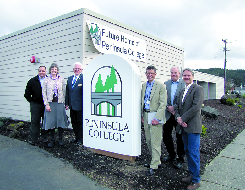 The Peninsula College Board of Trustees and president stand beside the new Peninsula College sign at the school's future Forks campus building Tuesday. Pictured from left are Dwayne Johnson