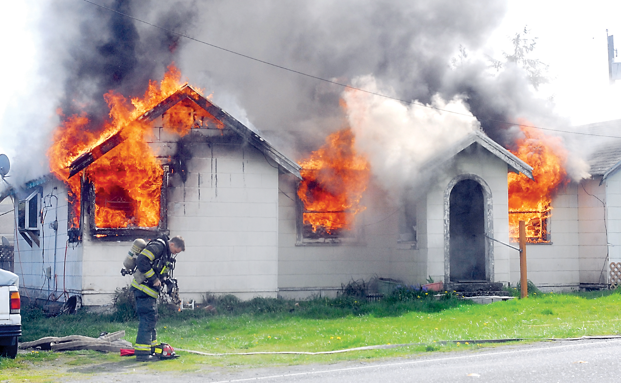 Port Angeles firefighter Kevin Denton prepares to attack a fire that destroyed this house at 4017 S. Fairmount Ave. in Port Angeles on Tuesday. Keith Thorpe/Peninsula Daily News