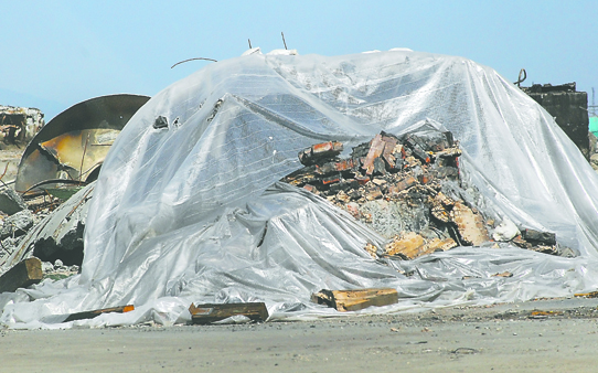 A plastic tarp covers the wreckage of the former Peninsula Plywood stack in Port Angeles on Friday. Keith Thorpe/Peniinsula Daily News