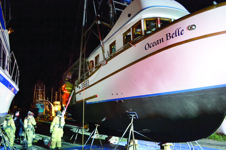 East Jefferson Fire-Rescue firefighters remove a smoking trash bag from the Port Townsend-based Ocean Belle just before midnight Tuesday. Bill Beezley/East Jefferson Fire-Rescue