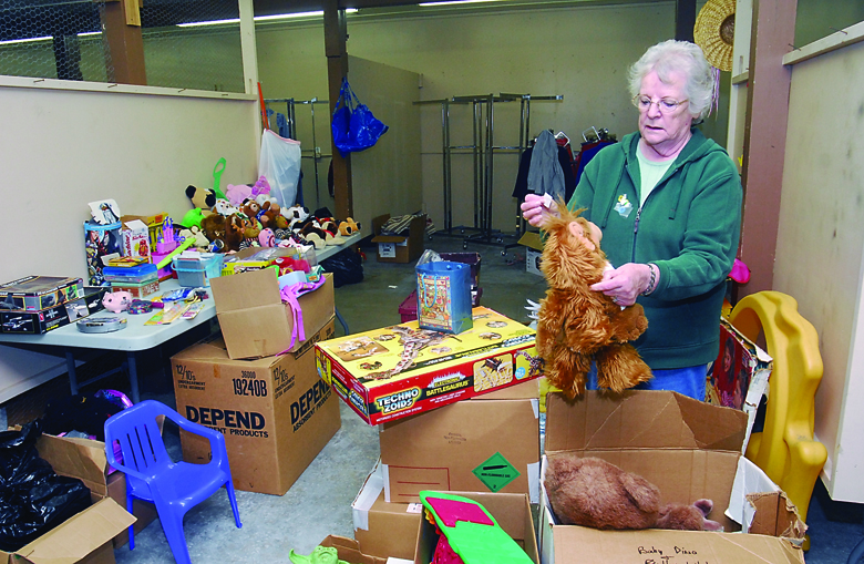 Nancy Hilt of Port Angeles examines a stuffed doll while stocking tables for this weekend's Kiwanis Garage Sale at the Clallam County Fairgrounds in Port Angeles. Keith Thorpe/Peninsula Daily News